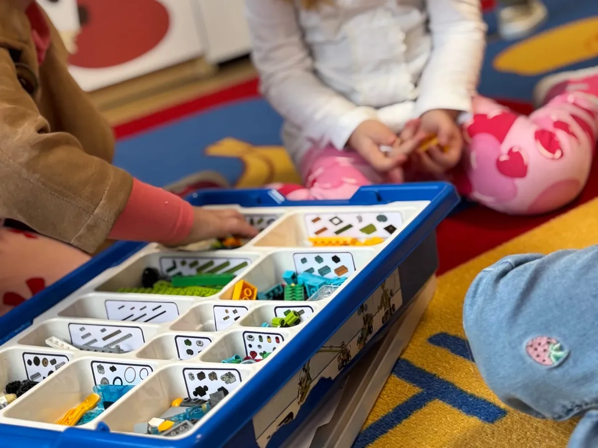 Zajęcia z robotyki — dzieci wybierają klocki LEGO z zestawu do budowy robotów